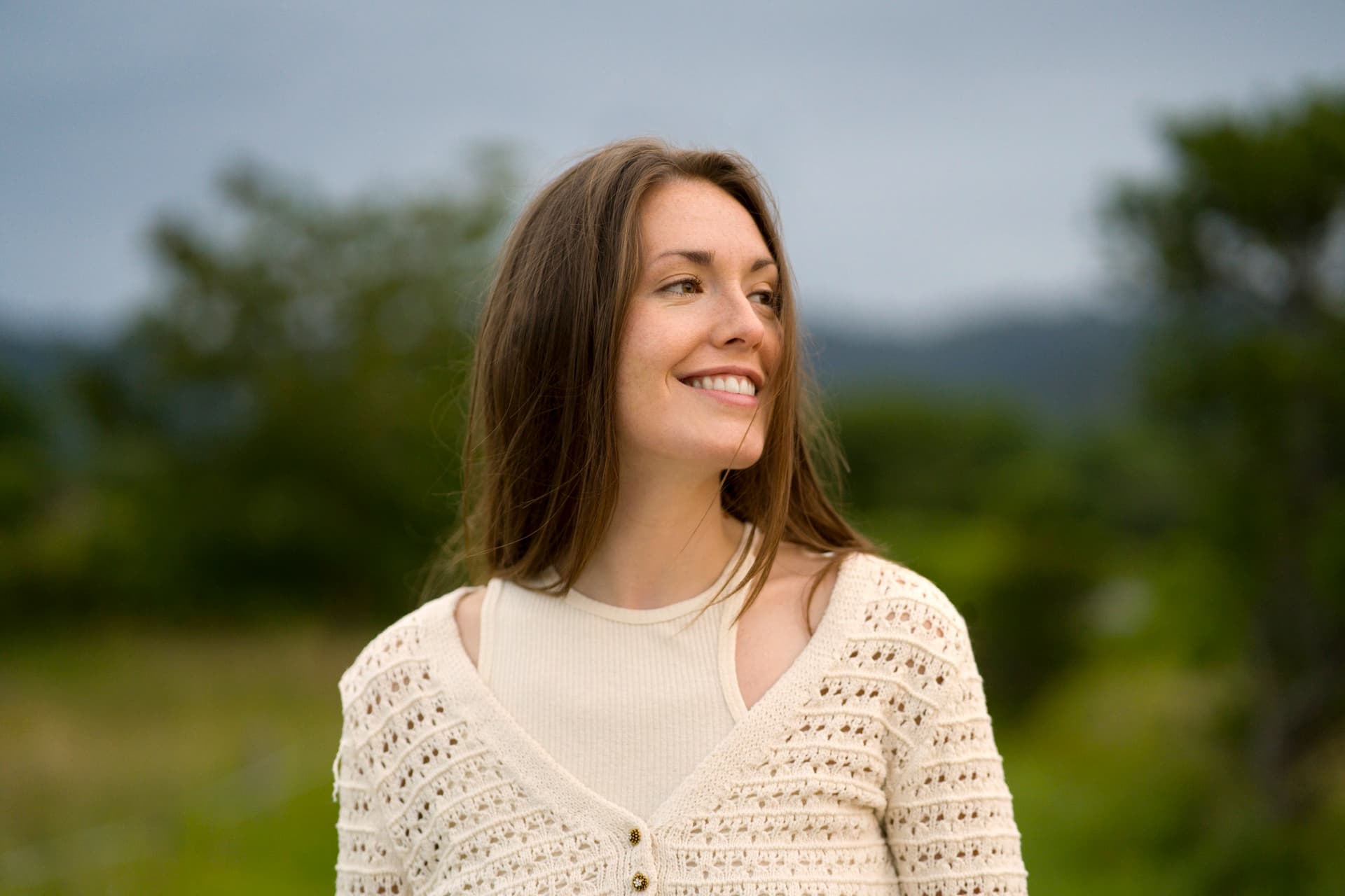 Smiling woman outdoors in a cream knit top