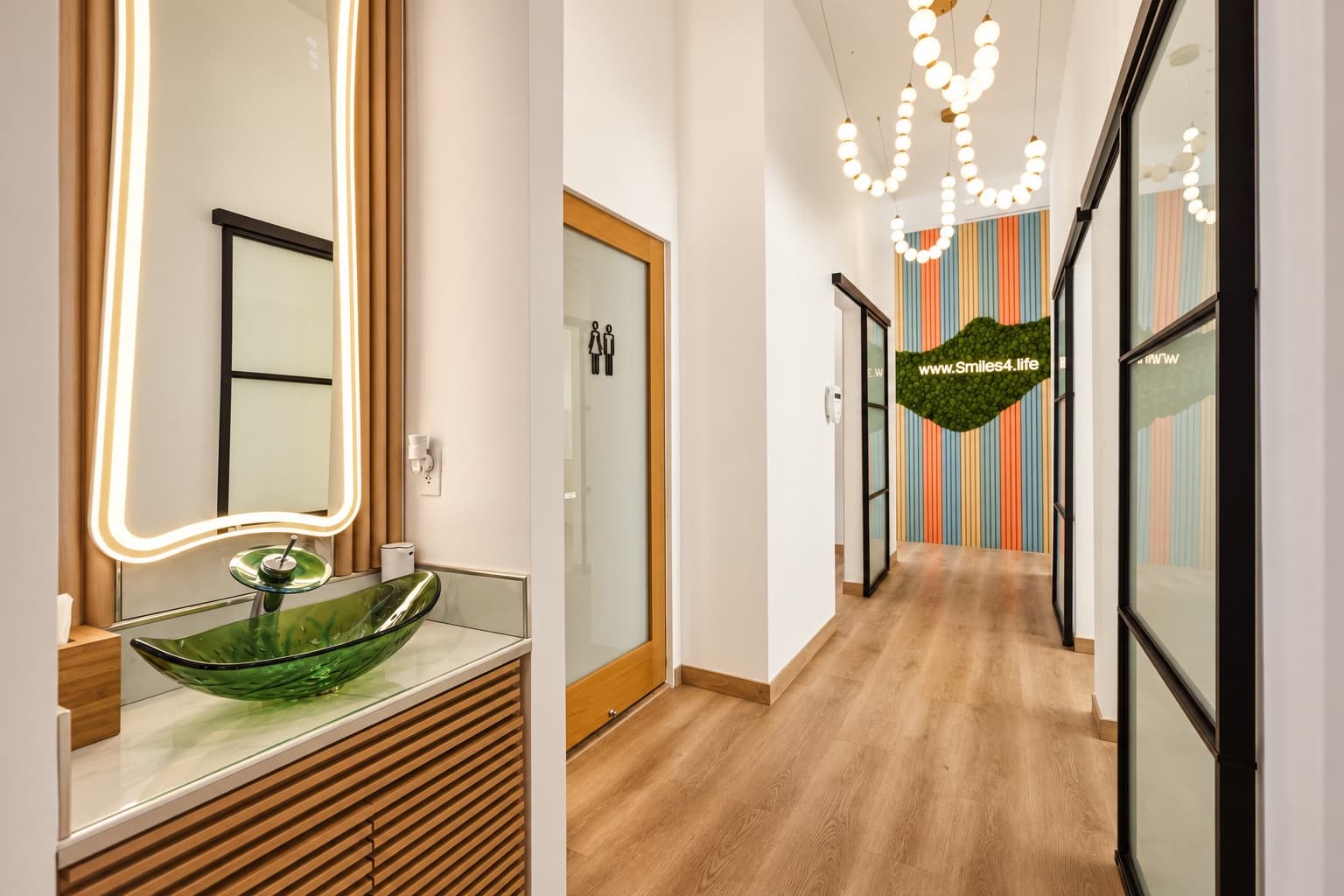 Hallway to the treatment rooms at Smiles4Life, with a glass vessel sink and colorful slat wall